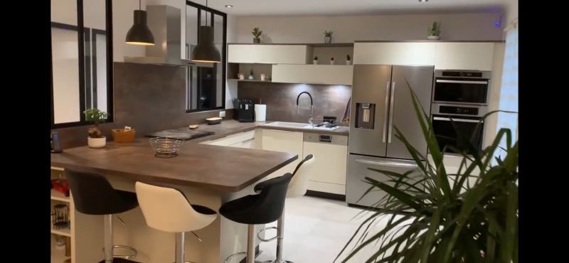 cuisine équipée Cuisine moderne avec un îlot, des chaises, et des appareils électroménagers en inox.